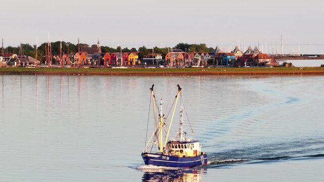 Fishing trawler boat sailing past a picturesque dutch village