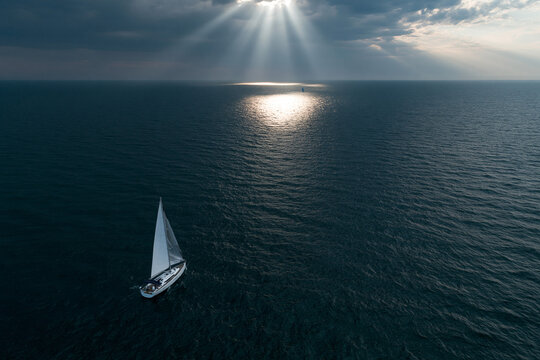 Sailboat on water under cloudy sky at sunset