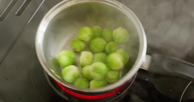 Boiling brussels sprouts in pot and stirring with wooden spatulas