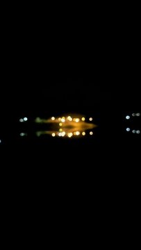 Abstract night scene featuring soft bokeh lights reflected on calm water in a peaceful dark environment