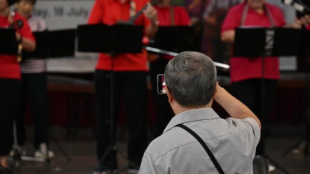 Man recording a live ukulele stage performance on his smartphone, close up of mobile phone screen at a music concert.