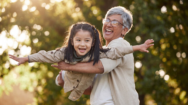 A happy grandmother lifting her granddaughter in the air like an airplane during a sunny afternoon at the park, showcasing love and multi-generational bonding.