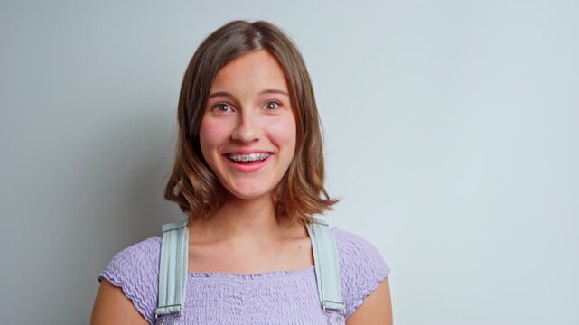 portrait of a happy young girl with metal braces on teeth laughing and showing a surprised expression due to good news captured in a professional studio setting with clear facial features
