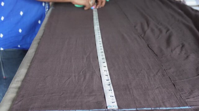 Tailor measuring dark fabric for custom dress making