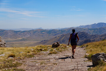 Fototapeta premium Female Trail Runner running towards the horizon with a scenic arid mountain view
