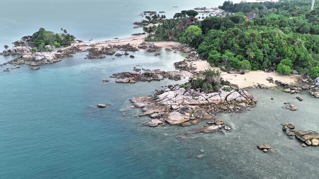 Cinematic Drone View of Teluk Karang Beach in Sungailiat Bangka Featuring Granite Rock Formations, Clear Tropical Waters and Hidden Sandy Coves