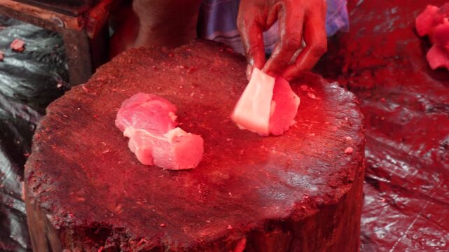 Worker cutting fresh pork at local market
