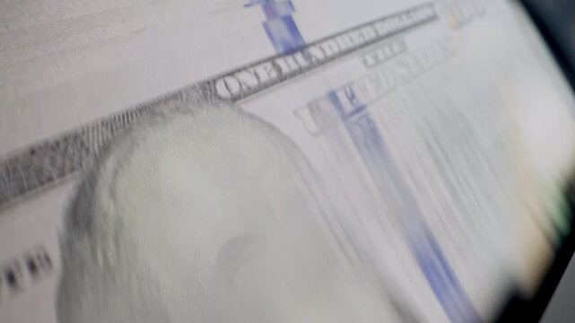 Close-up of US dollar banknotes counted by a cash counting machine. Perfect for currency exchange, international finance, banking and money transfer themes.