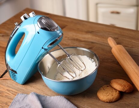 light blue stand mixer blending ingredients with fresh baked cookies and a rolling pin on a wooden board