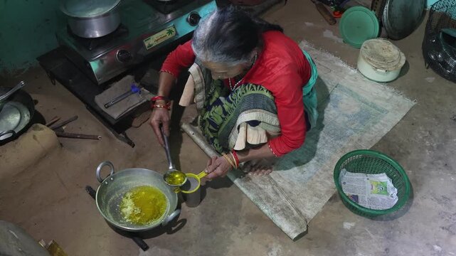 Raw video footage of a village woman making homemade ghee in a traditional rural kitchen in Uttarakhand, India, showcasing authentic cooking, village life, and poverty.