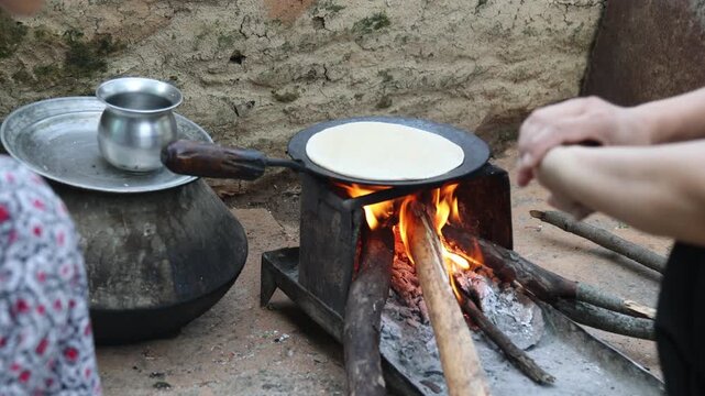Raw video footage of a village woman making traditional roti on a wood-fired stove in Uttarakhand, India, showcasing authentic rural cooking, village life, and poverty.
