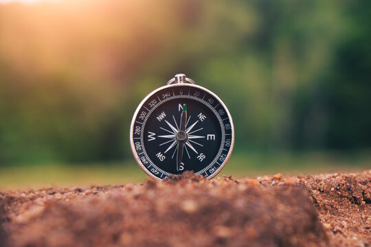 The compass by the river in the forest is a symbol of travel.