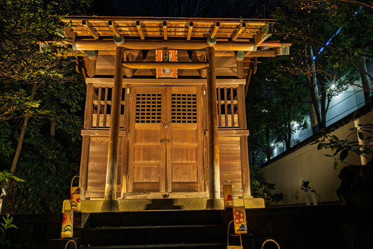 Front view of the solemnly illuminated Shinto shrine building at night in Koishikawa Korakuen January 2024