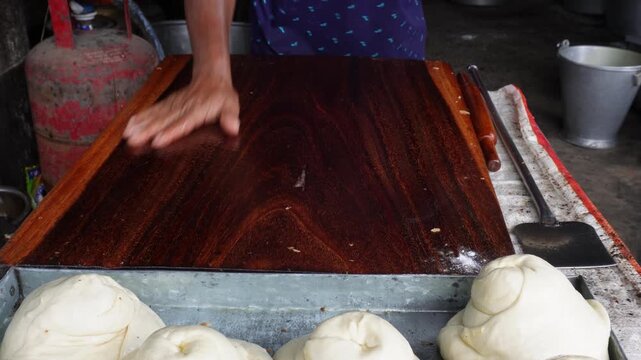 Rolling flatbread dough with wooden rolling pin