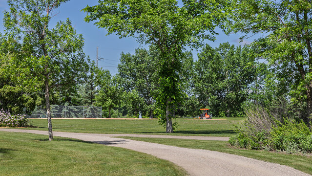 Urban park maintenance red tractor mowing the grass in a park.