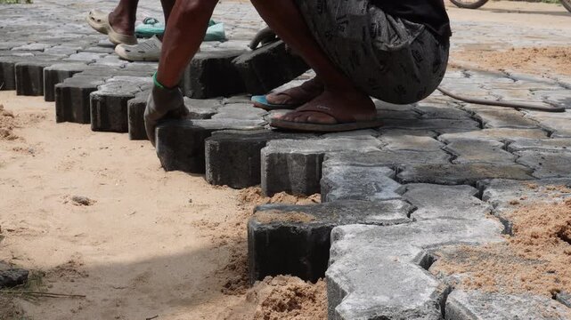 Worker installing interlocking paver blocks for new roadway