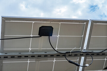 Close-up of solar panel backside mounting system and electric wires against blue sky. Renewable energy technology installation concept. © Juli