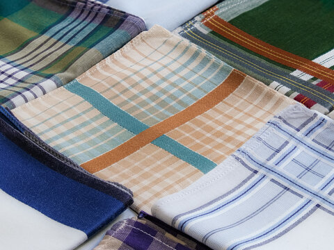 A colorful collection of folded men's handkerchiefs with geometric and plaid prints filling the entire frame.