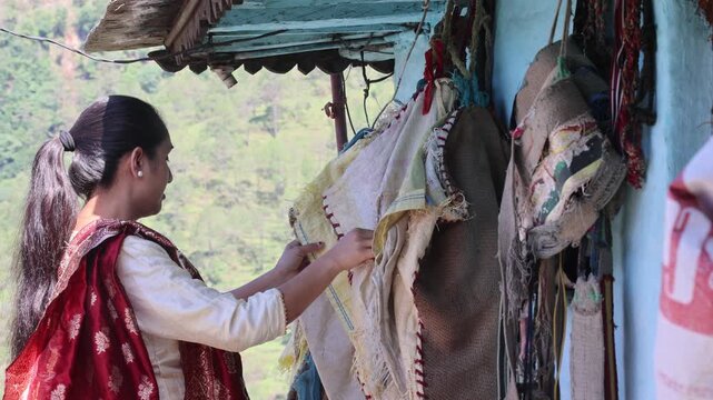 Raw video footage of a village woman hanging woven polypropylene and jute sacks outside her rural home in Uttarakhand, India, reflecting everyday village life, traditional practices, and poverty.