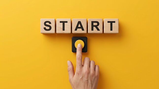 Hand pressing a yellow button on a black base, initiating the word START spelled out on wooden cubes against a vibrant yellow background.