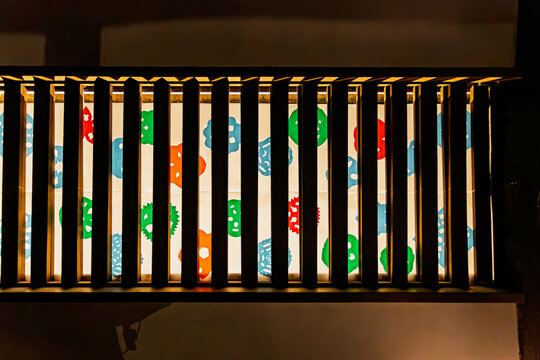 Artistic colorful paper-cut patterns illuminated behind a traditional wooden lattice window at Koishikawa Korakuen January 2024