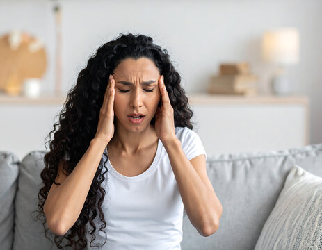 Woman experiencing severe migraine pain, holding her temples with closed eyes