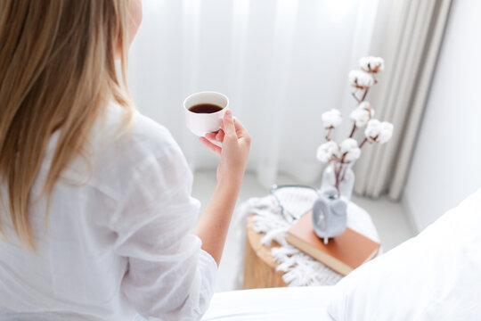 Woman drinking morning coffee in bed. Slow living, self-care, relaxation and mindfulness routine. Home interior, lifestyle moment, close up
