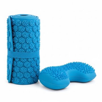Blue acupressure mat rolled with strap and U-shaped neck pillow on white background, spiky massage set for pain relief relaxation and muscle tension therapy
