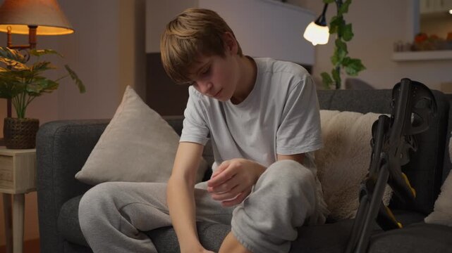 Young boy recovering from a leg fracture sits on a couch with his plaster cast, facing the physical limitations of injury and the challenges of returning to everyday life.