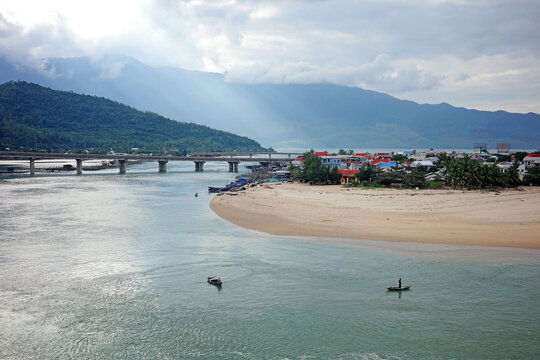 lang co - vietnam - december 30 2025: wide angle view of lang co sand spit and hai van bridge with local fishing boats under cloudy sky