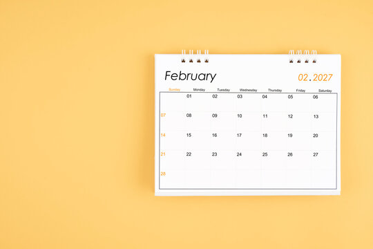 February 2027 desk calendar on yellow color background, position with copy space.