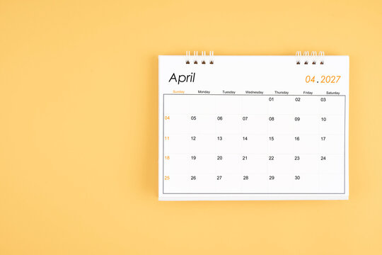 April 2027 desk calendar on yellow color background, position with copy space.
