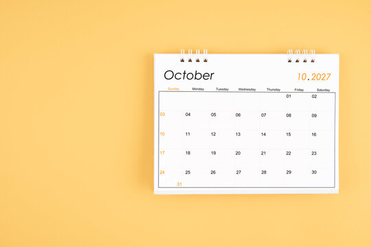 October 2027 desk calendar on yellow color background, position with copy space.