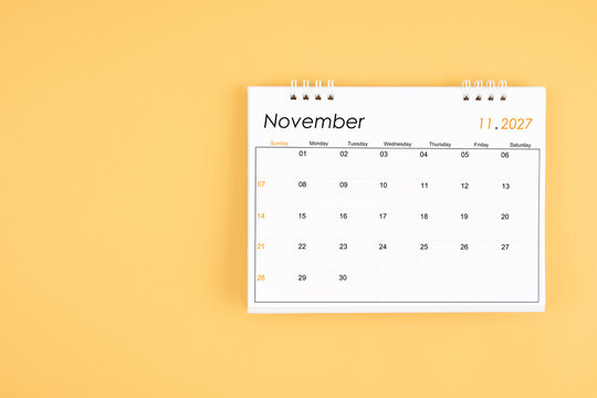 November 2027 desk calendar on yellow color background, position with copy space.