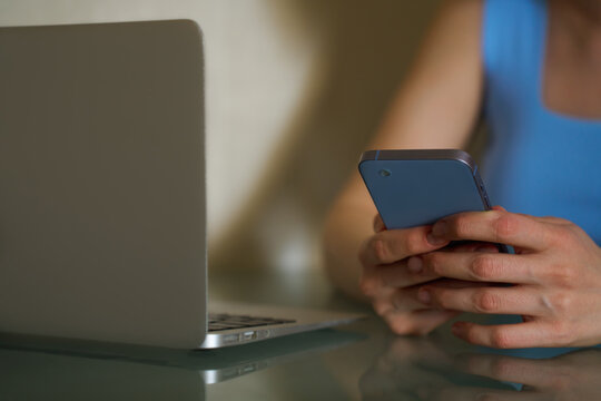 Woman using smartphone and laptop in office setting