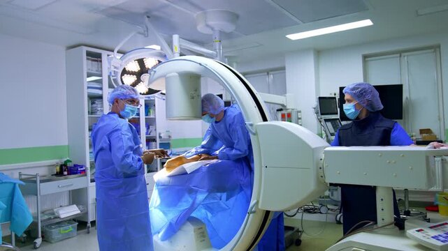 X-ray machine is placed over the patient's leg. Team of medics perform operation on the limb.