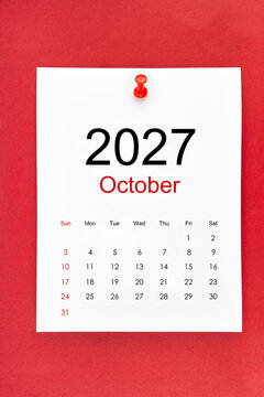 October 2027 calendar page with push pin on red color background.