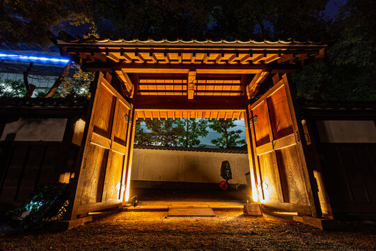 View through the wide open wooden gate illuminated at night in Koishikawa Korakuen Garden January 2024