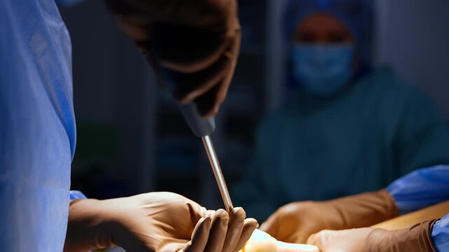 Unrecognized doctor uses a long screw-driver inserting orthopedic screws into the heel. Calcaneal osteotomy or heel realignment. Close up.
