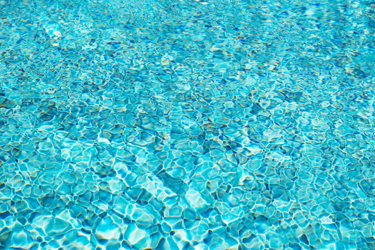 Refreshing clear blue pool surface with sunlight reflections