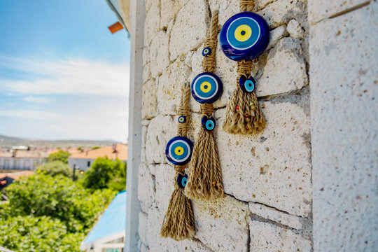 Blue evil eye charms hanging on a stone wall outside