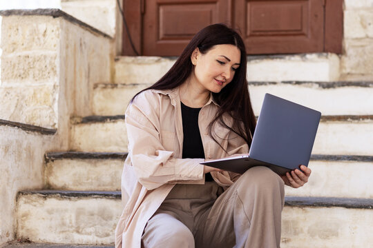 Young woman working on laptop while sitting on outdoor steps