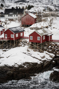 Red cabins on rocky snow-covered coast in winter Lofoten