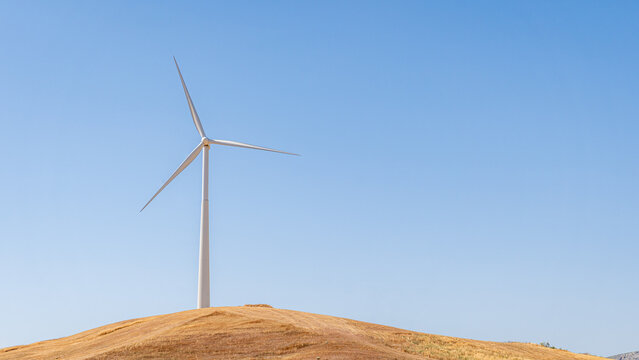 Wind turbine on a hill against a clear blue sky