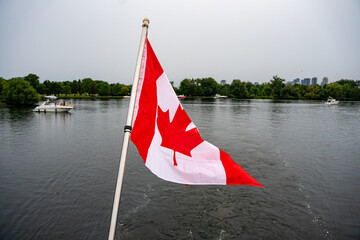 Fototapeta premium Close up of Canadian flag over island waterway.