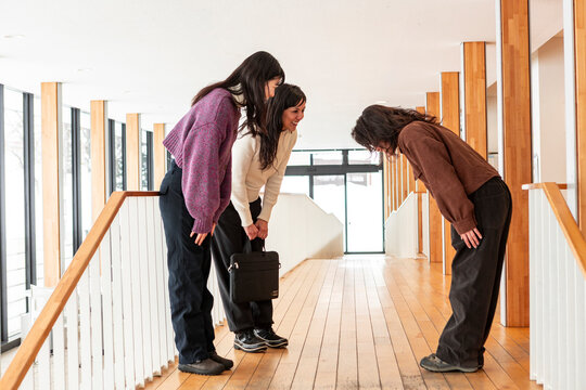 Japanese women bowing in office hallway greeting