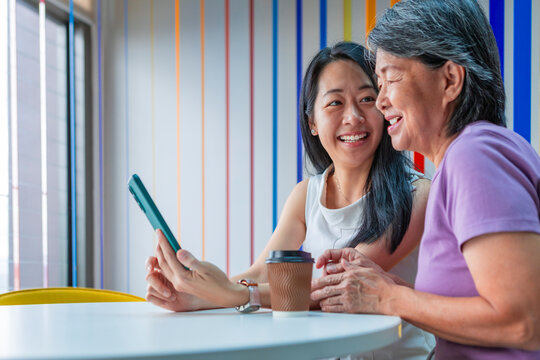 Senior Asian mother and daughter using smartphone together