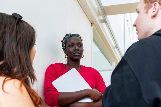 Multiethnic student group discussing coursework in hallway
