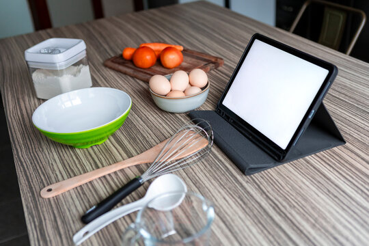 Home baking setup with tablet recipe and tomato on table