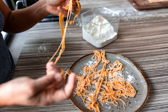 Handmade pasta being stretched and dusted with flour